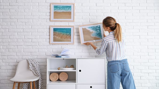 A woman hanging art prints on a wall